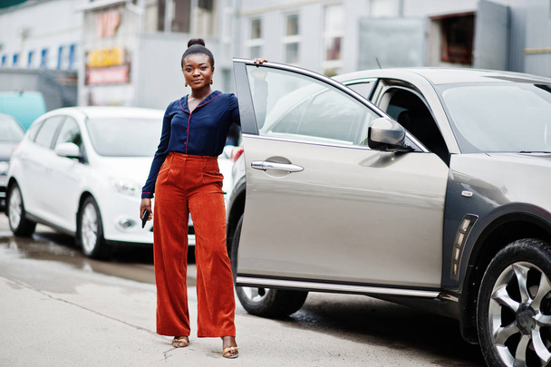 Rica mujer africana de negocios en pantalones naranjas y camisa azul posado
 - Foto, Imagen