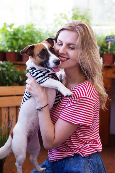Όμορφη νεαρή γυναίκα που παίζει με ένα σκυλί στη βεράντα, όπου t - Φωτογραφία, εικόνα