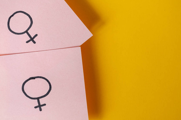 Dva růžové nálepky s genderovými symboly Venuše nad žlutým pozadím. Koncepce homosexualita. - Fotografie, Obrázek