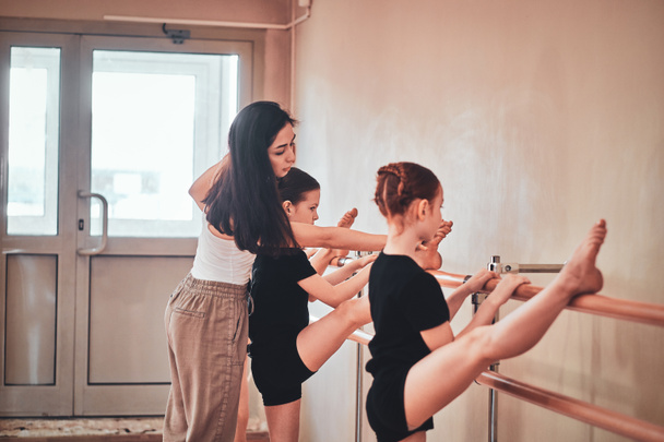 Усердные девушки занимаются стрейчингом со своим талантливым тренером
 - Фото, изображение