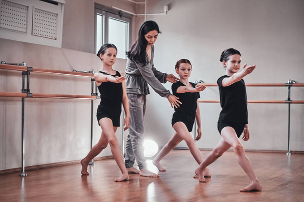 Три молодые девушки проходят балетную подготовку со своим привлекательным учителем
 - Фото, изображение