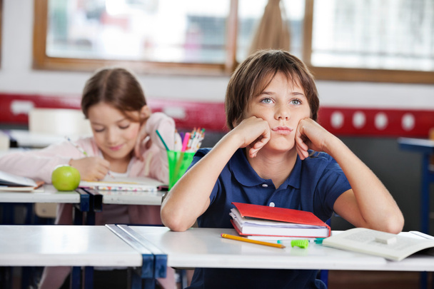 Bored Schoolboy Looking Away Sitting At Desk In Classroom - Photo, Image
