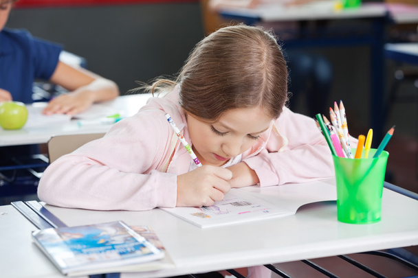 Schoolgirl Drawing In Book At Desk - Фото, изображение