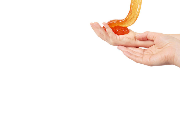 criança jogando lodo laranja com a mão, brinquedo transparente
 - Foto, Imagem
