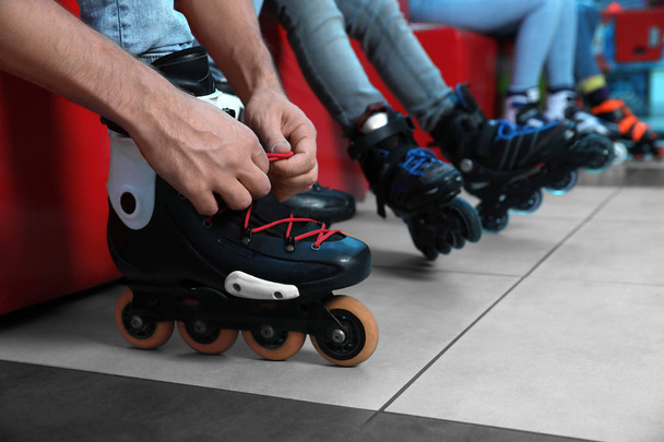 Man putting on roller skates indoors, closeup - Fotó, kép