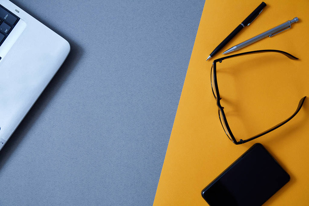 Blogging, blog and blogger or social media concept: a laptop, glasses and an external hard drive on a grey and yellow background. Flat lay - Foto, Imagem