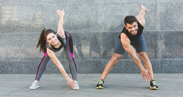 Young man and woman doing morning exercises outdoor - Foto, Imagen