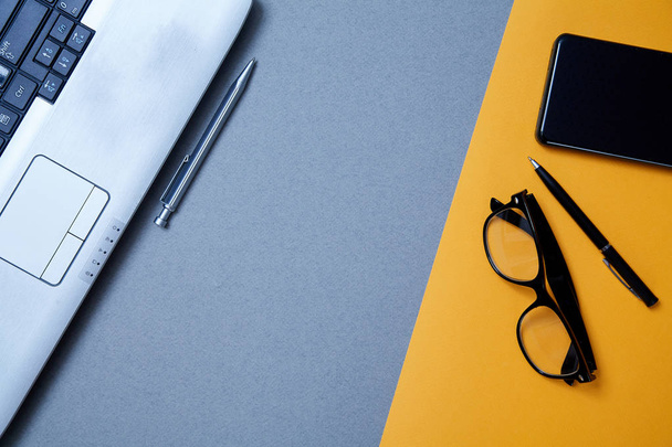Blogging, blog and blogger or social media concept: a laptop, glasses and an external hard drive on a grey and yellow background. Flat lay - Photo, Image