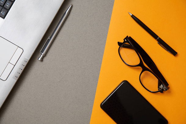 Blogging, blog and blogger or social media concept: a laptop, glasses and an external hard drive on a grey and yellow background. Flat lay - Foto, imagen