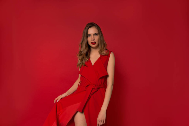 Elegante mujer joven de moda con fantástico vestido rojo posando sobre fondo rojo aislado
  - Foto, imagen