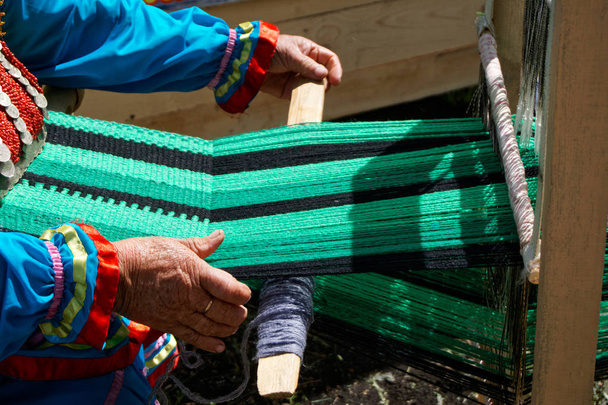 Una donna anziana gira su un telaio artigianale. All'aperto
 - Foto, immagini