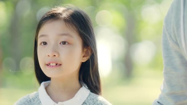 彼女が見るものに驚いた小さなアジアの女の子の顔のクローズアップ - 映像、動画