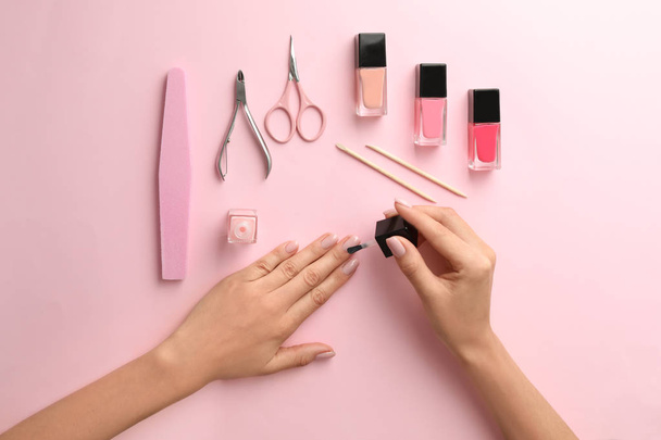 Woman applying nail polish on color background, top view - Foto, immagini