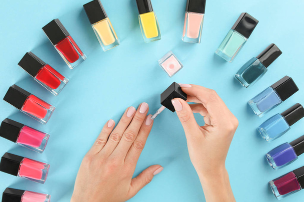 Woman applying nail polish on color background, above view - Valokuva, kuva