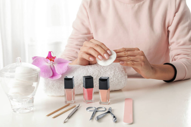 Woman removing polish from nails with cotton pad at table, closeup - Foto, afbeelding