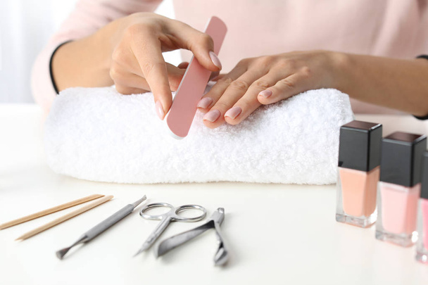 Woman filing nails covered with polish at table, closeup - Foto, immagini