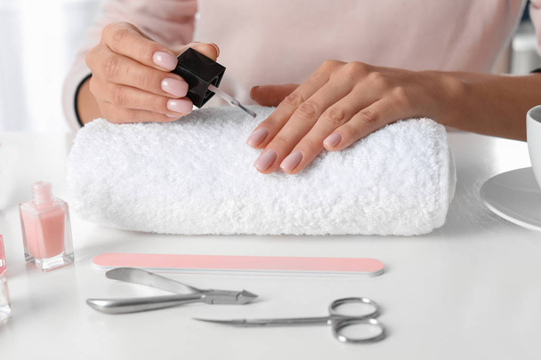 Woman applying nail polish at table, closeup. At-home manicure - Foto, afbeelding