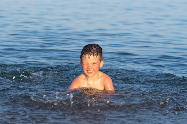 Un garçon de trois ans nage dans la mer au coucher du soleil avec son frère
. - Photo, image