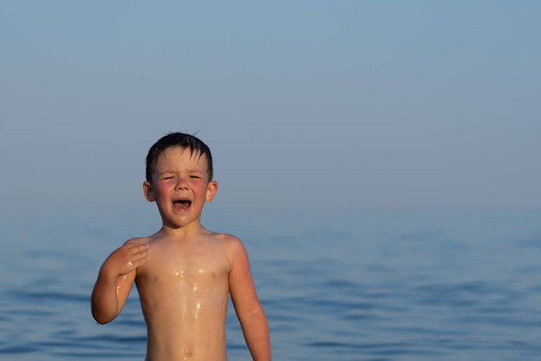 Chłopiec z trzech lat jest pływanie w morzu o zachodzie słońca z bratem. - Zdjęcie, obraz