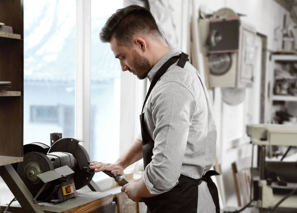 Young working man using grinding machine at carpentry shop - Φωτογραφία, εικόνα