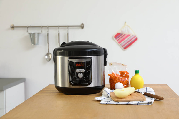 New modern multi cooker and products on table in kitchen - Foto, imagen