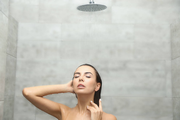 Beautiful young woman taking shower in spa center - 写真・画像