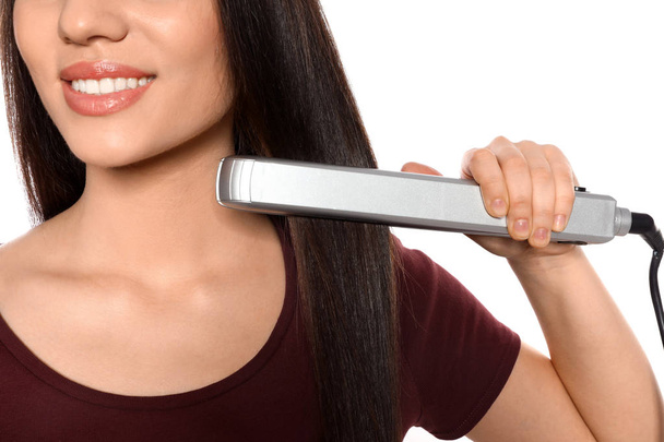Happy woman using hair iron on white background, closeup - Foto, Bild