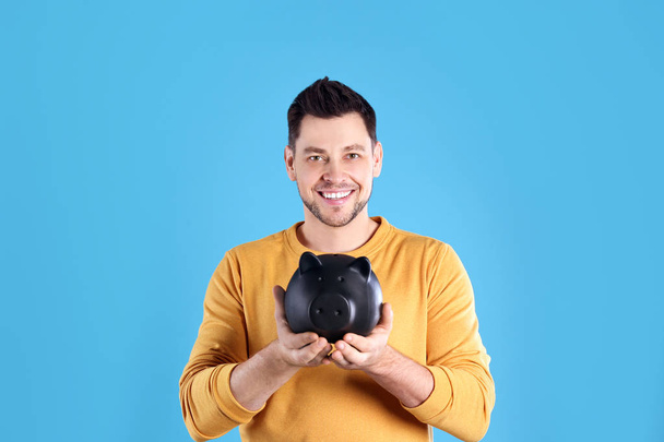 Man with piggy bank on color background - Valokuva, kuva