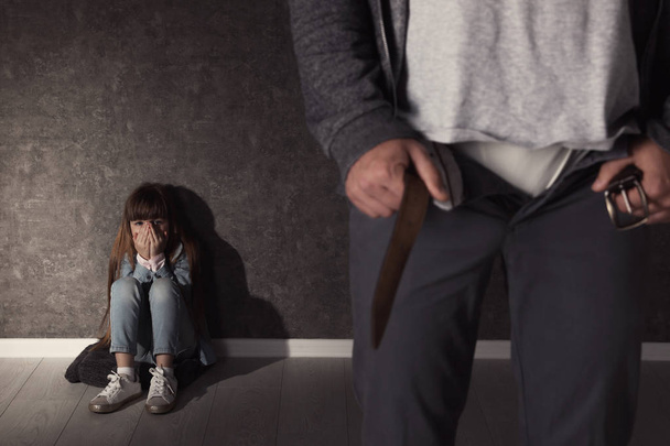 Man with unzipped pants and scared little girl indoors. Child in danger - 写真・画像