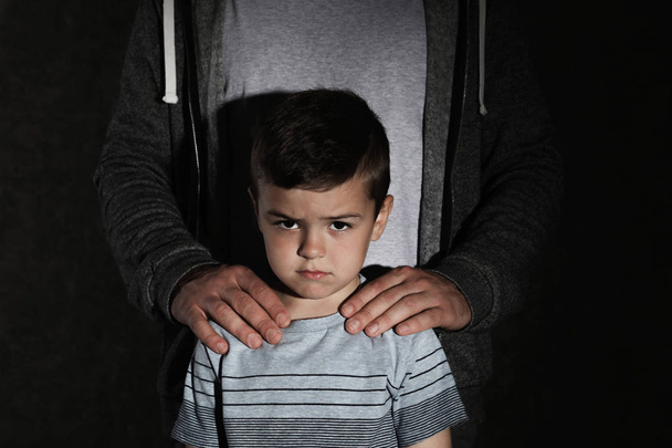 Scared little boy and adult man on dark background. Child in danger - Fotoğraf, Görsel