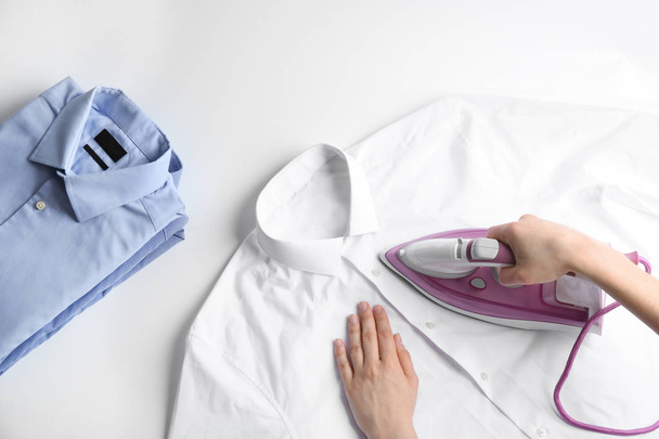 Woman ironing shirt on light background, top view - Zdjęcie, obraz
