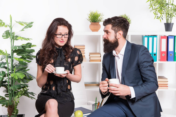 Office rumors. Office coffee. Couple coworkers relax coffee break. Share coffee with with colleague. Flirting colleagues. Bearded man and attractive woman. Man and woman conversation coffee time - Фото, изображение