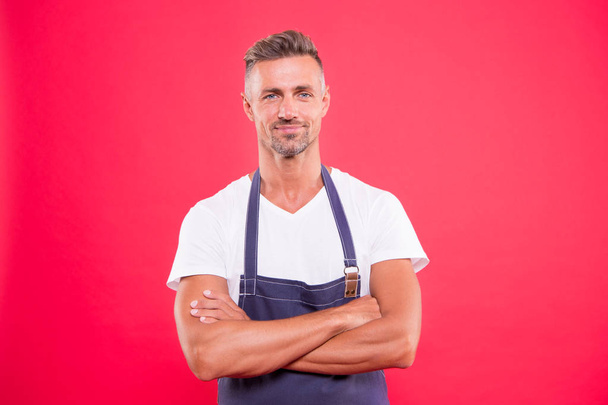 Homemade is best. Cook with bristle crossed arms on chest red background. Cook food at home. Man mature cook posing cooking apron. Fine recipe. Ideas and tips. Chief cook and professional culinary - Photo, image