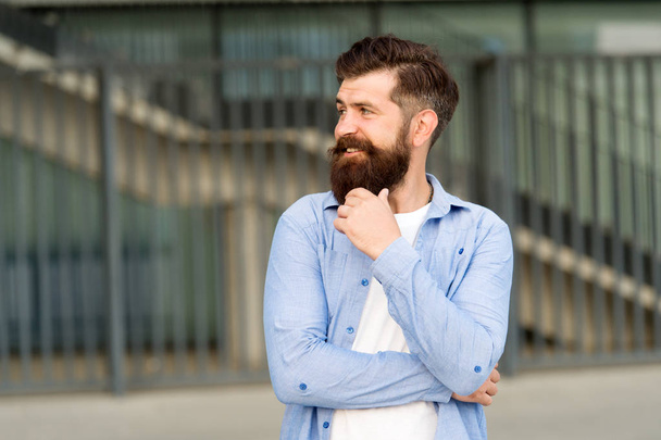 What is on his mind. Pensive hipster thinking pleasant thoughts. Man bearded hipster urban background. Regular walk in city center. Confident hipster stand in street alone. Right here and now - Фото, изображение