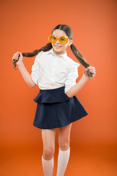 I am a girl and I am smart. Little smart schoolgirl on orange background. Adorable child with smart look through fancy glasses. Fashionable small kid wearing sunglasses in smart and chic style - Fotó, kép