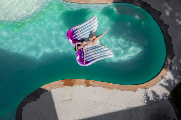Μια όμορφη μελαχρινή μοντέλο μαγιό απολαμβάνει αυτή διακοπές στην πισίνα - Φωτογραφία, εικόνα