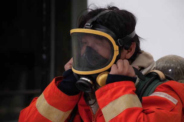 Feuerwehrmann mit Maske und Schutzanzug zur Brandbekämpfung vor Ort - Foto, Bild
