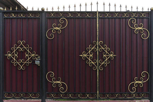 Porte de clôture en fer forgé ornée et belle peinte en brun écarlate et or. Une photo d'une vieille porte naturelle à utiliser comme texture
 - Photo, image
