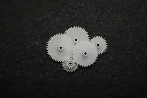 White wheel gears are on black texture background - Fotoğraf, Görsel