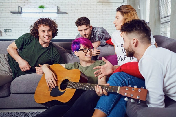 Grupo de amigos com uma guitarra em uma festa em um quarto
. - Foto, Imagem