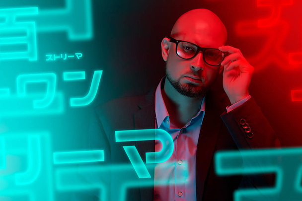 Attractive bald man with beard with glasses on neon light background - Fotoğraf, Görsel
