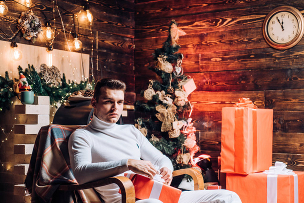 Surprise for sweetheart. Merry christmas and happy new year. Christmas gifts. Man handsome with gift box surprise waiting midnight. Man well groomed hipster sit in decorated for christmas interior - 写真・画像