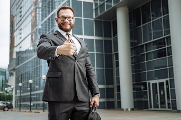 Portrait of a happy business man showing his thumb up on the background of the business center - Foto, Imagen