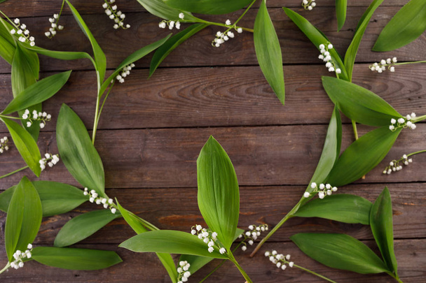 The decor of the flowers of lily of the valley on the background of vintage wooden boards. Vintage background with frame of flowers and place under the text. Flat lay. - Foto, afbeelding