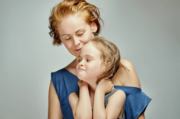 Bela filhinha com a mãe posando em estúdio em fundo cinza
 - Foto, Imagem
