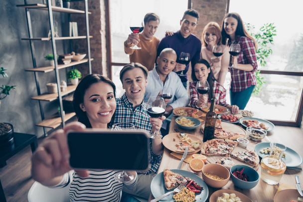 Close up photo friendly event together diversity different race guys raise glasses red beverage telephone make take tradition selfies sit table shirts sweater pullover loft cafe restaurant indoors - Photo, image