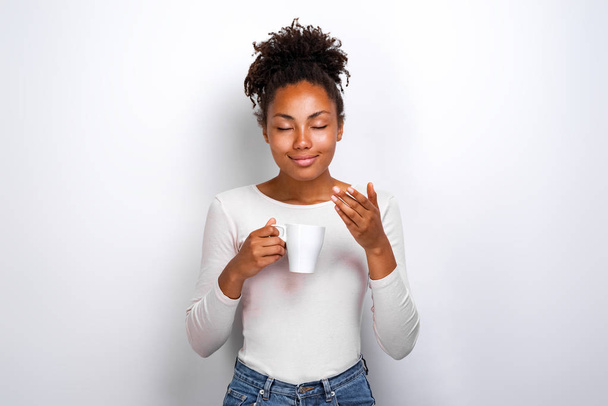 Pleased cute mulatto girl inhales the aroma of coffee - Foto, Imagem
