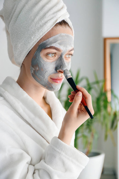 Young woman applying clay mask at home - 写真・画像