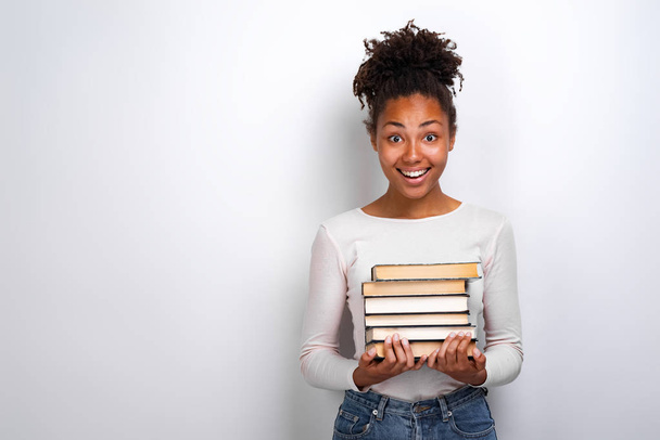 Portrait of an excited young girl holding books over white background. Back to school - Photo, image