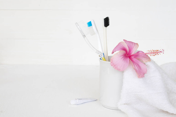 toothbrush ,toothpaste health care for oral cavity with terry cloth ,pink flowers hibiscus arrangement flat lay style on background white  - Photo, Image